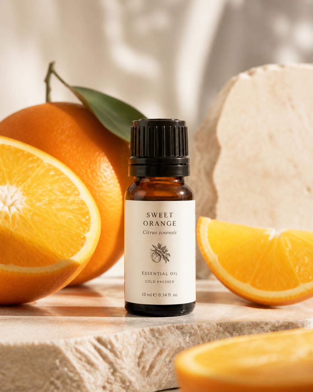 Amber Wellthious essential oil bottle beside fresh sweet oranges on a stone surface